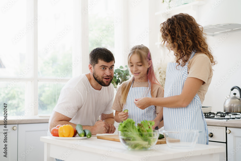 Family of three standing in kitchen and cooking meal together