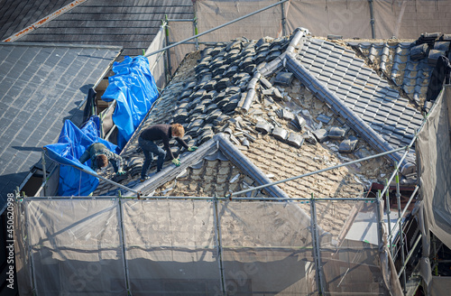 People working to tile a roof damaged by natural disaster