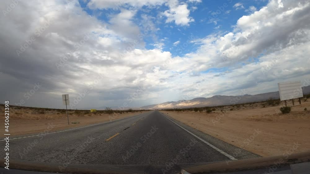 Driving through the Mojave Desert towards the distant mountains on a cloudy day - driver point of view Driving through the Mojave Desert towards the distant mountains on a cloudy day - driver point of view