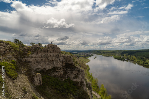 Fototapeta Naklejka Na Ścianę i Meble -  Man stands on top of a cliff by the river
