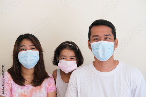Happy Asian family wearing protective medical mask in their home photo