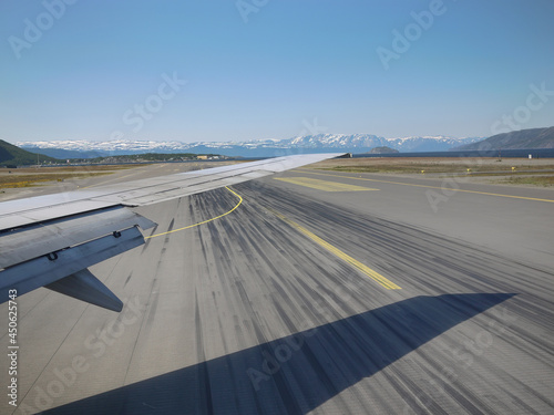 Airplane wing takoff on runway with snow mountain background