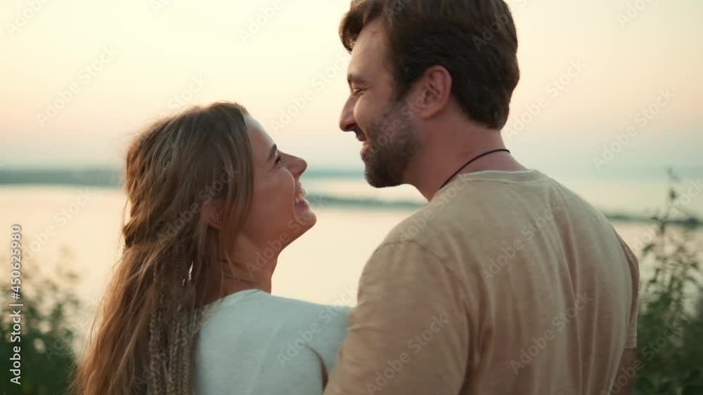A lovely couple man and woman are kissing then looking to the sunset outside at nature A lovely couple man and woman are kissing then looking to the sunset outside at nature