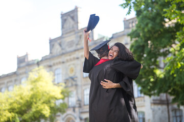 Friends hugging each other after graduation and feeling happy