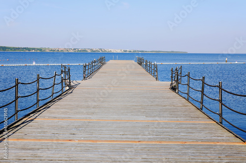 The pier near beach against blue sky in sunny day. Adriatic coast and sea in Slovenia. Holiday and travel concept. 