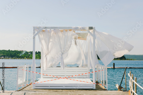 Landscape outdoor cabana bed on the pier near beach in sunny day. Adriatic coast and sea in Slovenia. Holiday, wedding and celebration concept. 