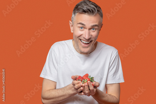 Happy man holding strawberries in his palms
