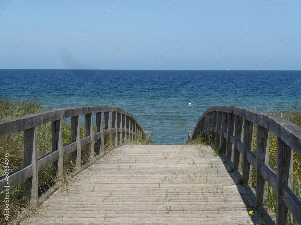 Holzbrücke auf dem Weg zum Meer mit blauem Himmel