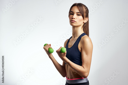 pretty athletic woman with dumbbells in hands pumping up muscles fitness