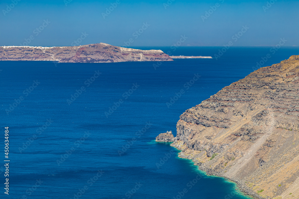 Cliff wall of Santorini island, Greece. Clear blue ocean, sea, with copy space, place for text. Shore, coast of dry rocks