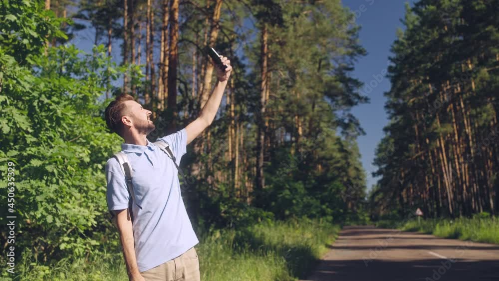 Serious man holding phone up to find mobile network in forest, tourist got lost Serious man holding phone up to find mobile network in forest, tourist got lost