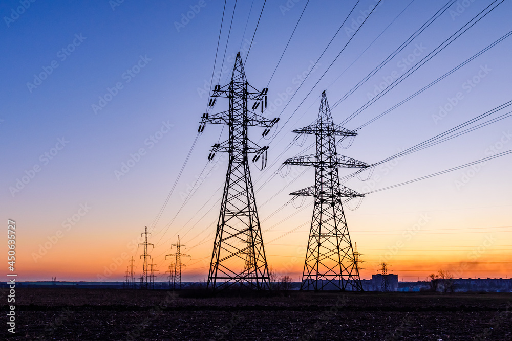 Fototapeta premium High voltage power line in a field at sunset