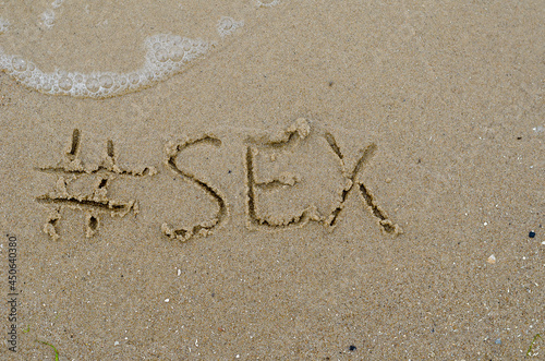 Hashtag and the word SEX written in the wet sand. Handwritten wo © Mikhail