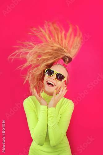 A beautiful cheerful girl in sunglasses on a pink background.