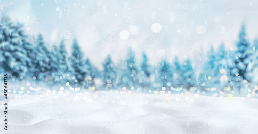 Beautiful winter natural background of snow and blurred forest, Gently falling snow flakes and christmas lights against blue morning sky, free space for your decoration.  Wide format.