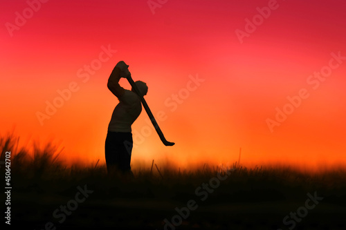 Miniature people toy figure photography. Silhouette of men golfer swing his stick at meadow field hill when sunset sunrise