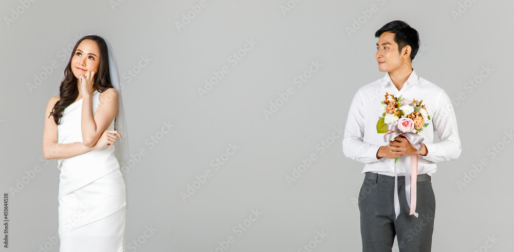 Young attractive Asian couple, man wearing white shirt, woman wearing white dress with wedding veil standing apart. Man holding bouquet of flowers. Concept for pre wedding photography Young attractive Asian couple, man wearing white shirt, woman wearing white dress with wedding veil standing apart. Man holding bouquet of flowers. Concept for pre wedding photography