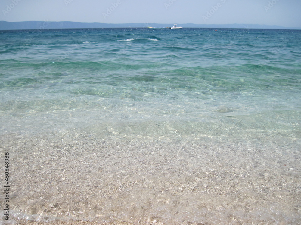 Scenic shining view of the clear water of Adriatic Sea on a sunny summer day. Colorful natural fresh background for creative illustration with shiny blur effect. Bright nautical scape beauty closeup