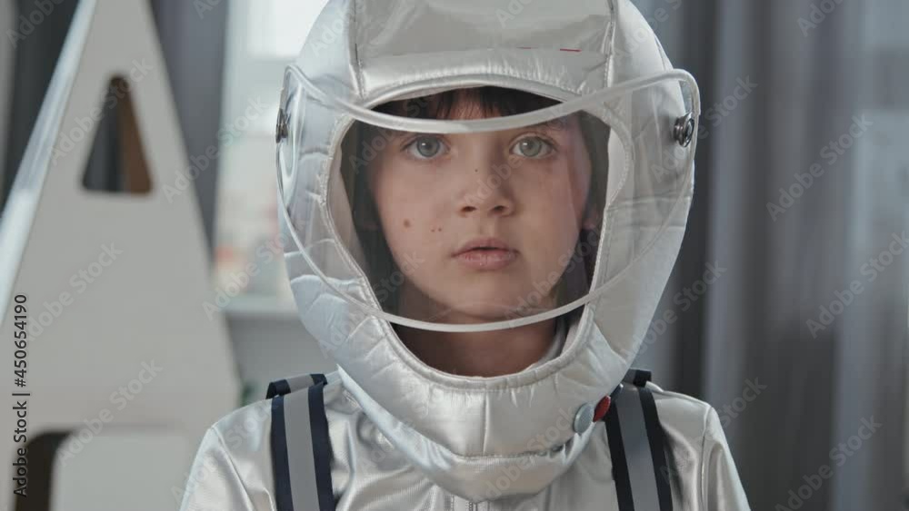 Portrait close up of serious 6-year-old boy in spacesuit posing for camera Portrait close up of serious 6-year-old boy in spacesuit posing for camera