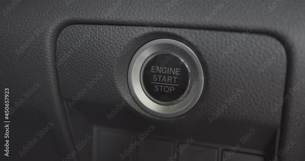 Automobile start-stop engine button blinking white after a single push (without pressing a brake pedal). Index finger push an automatic start engine to ignite the internal combustion engine system. Automobile start-stop engine button blinking white after a single push (without pressing a brake pedal). Index finger push an automatic start engine to ignite the internal combustion engine system.
