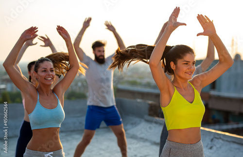 Group of happy fitness people training together outdoors, living active healthy lifestyle