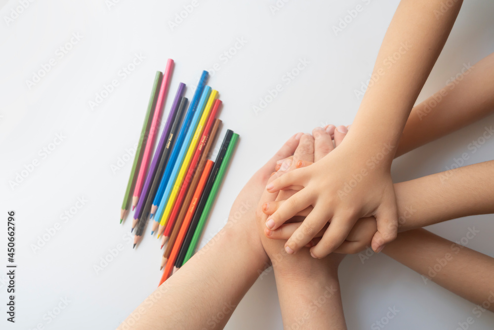Crayons and four children's hands on a white background. education concept. Concept of kinder education during the pandemic period. Crayons and four children's hands on a white background. education concept. Concept of kinder education during the pandemic period.