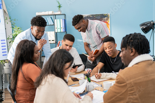 A group of ambitious, experienced employees in a large office are discussing work details at a business conference. The department head distributes tasks to each colleague, they talk among themselves