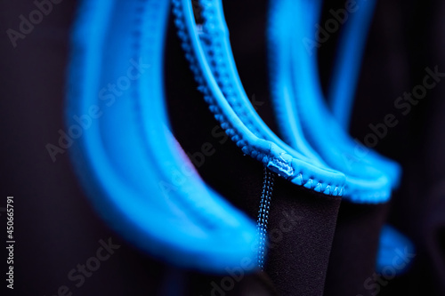Closeup macro of wetsuits hung up on coat hangers in a wet room cloak room with shallow depth of field