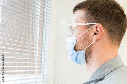 Closeup of tired doctor, lab tech wearing face mask and goggles, lost hope due to many patient deaths,looking at distance with sad gaze,fear and anxiety in eyes. fighting covid-19 pandemic. Healthcare