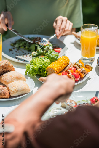 Cropped view of grilled vegetables near blurred couple outdoors