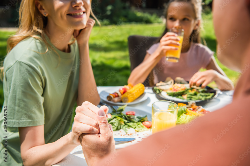 Parents holding hands near food and blurred kid outdoors