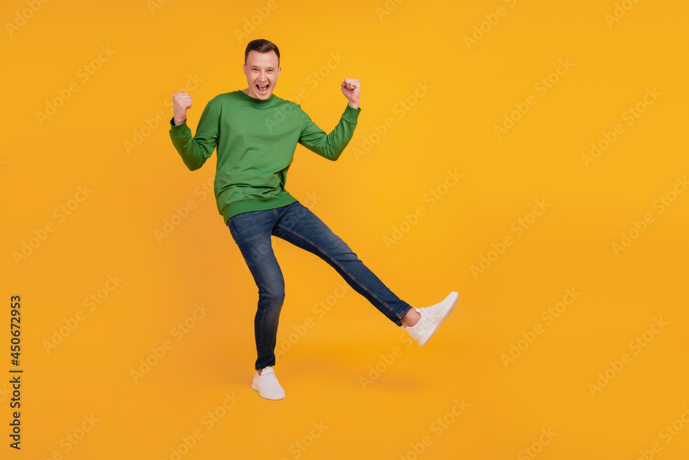 Portrait of nice attractive winner guy celebrate victory cheering on yellow background