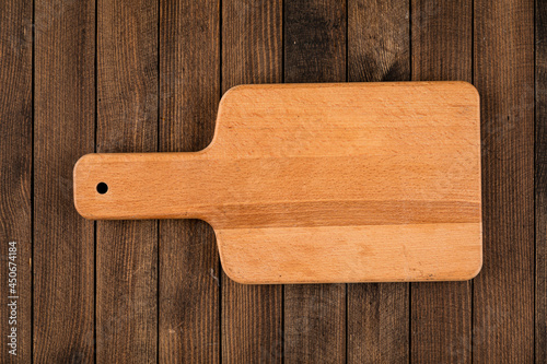 Top view on light brown wooden cutting board on a wooden background