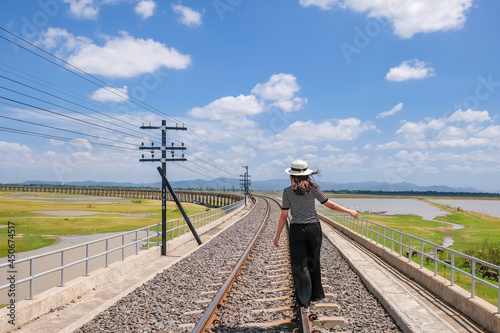 Beautiful Asian girl with curly natural hair on nature in forest on railway track. Happy girl Walk on railroad at dawn during summer time and Cheerful mood at Khok Salung, Lopburi, amazing Thailand. photo