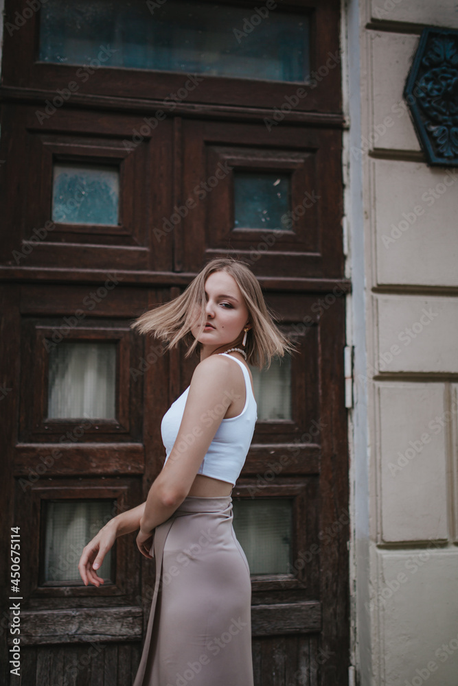 Fototapeta premium a beautiful young girl is walking around the city, spinning, dancing on the street