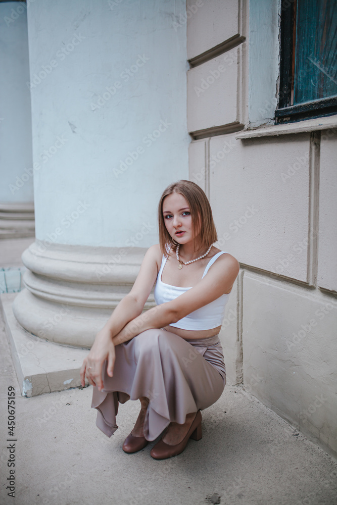 Fototapeta premium a beautiful girl in a skirt and top walks near the theater