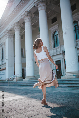 a beautiful young girl is walking around the city, spinning, dancing on the street
