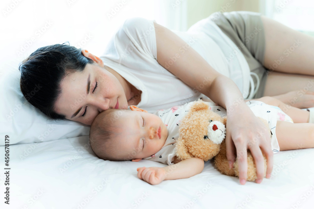 Young beautiful mother with her baby sleeping together in a bedroom at home Young beautiful mother with her baby sleeping together in a bedroom at home