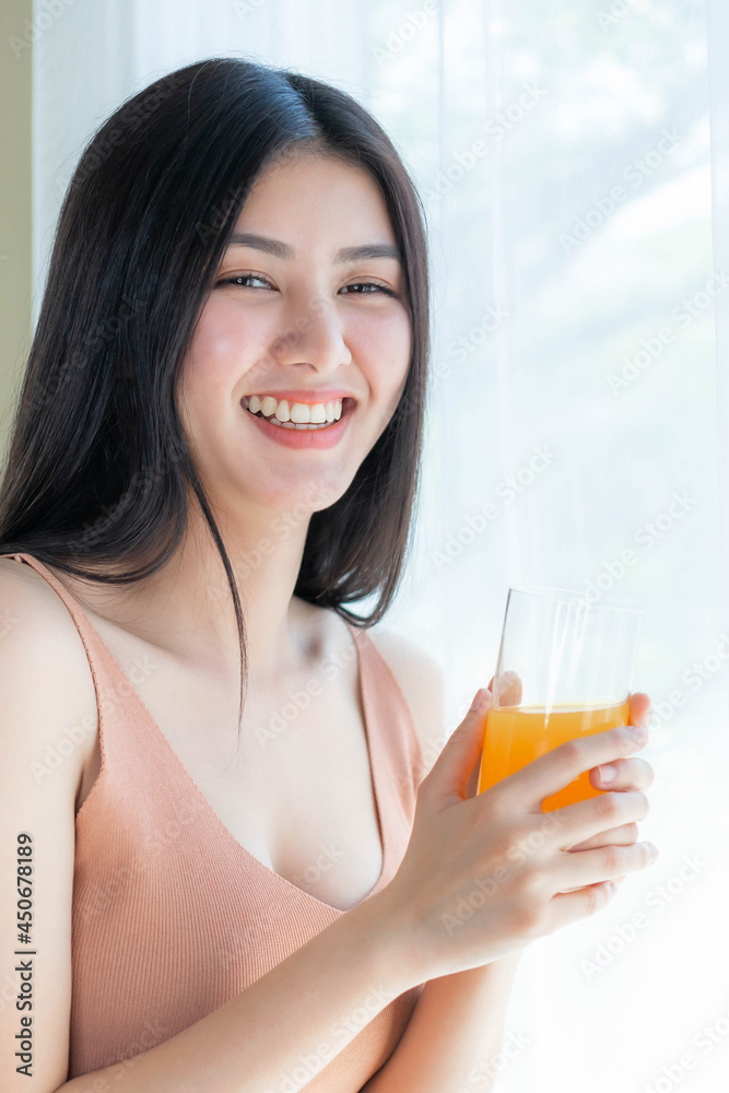Beautiful beauty woman Asian cute girl feel happy drinking orange juice for  good health in the morning , enjoying time in her home white bedroom  background - lifestyle beauty woman concept Stock