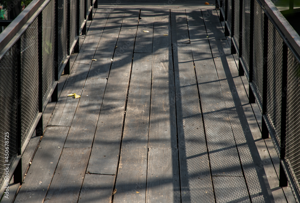 Old brown rustic Wooden walkway with sunlight shine passed through trees and make shadow on the floor. Copy space, area for text or lettering, Selective focus.