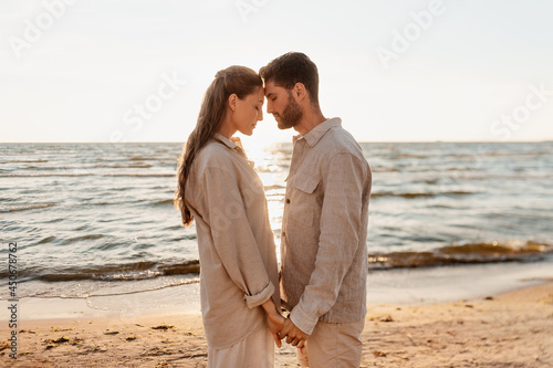 leisure  relationships and people concept - happy couple holding hands on summer beach