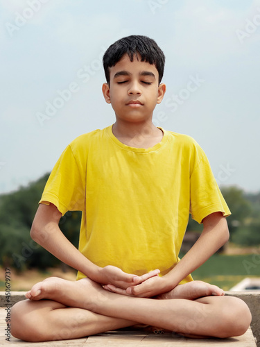 A young indian cute kid doing yoga lotus pose  (padmasana).