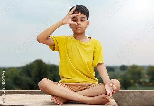 A young indian cute kid doing yoga anulom vilom pose.
