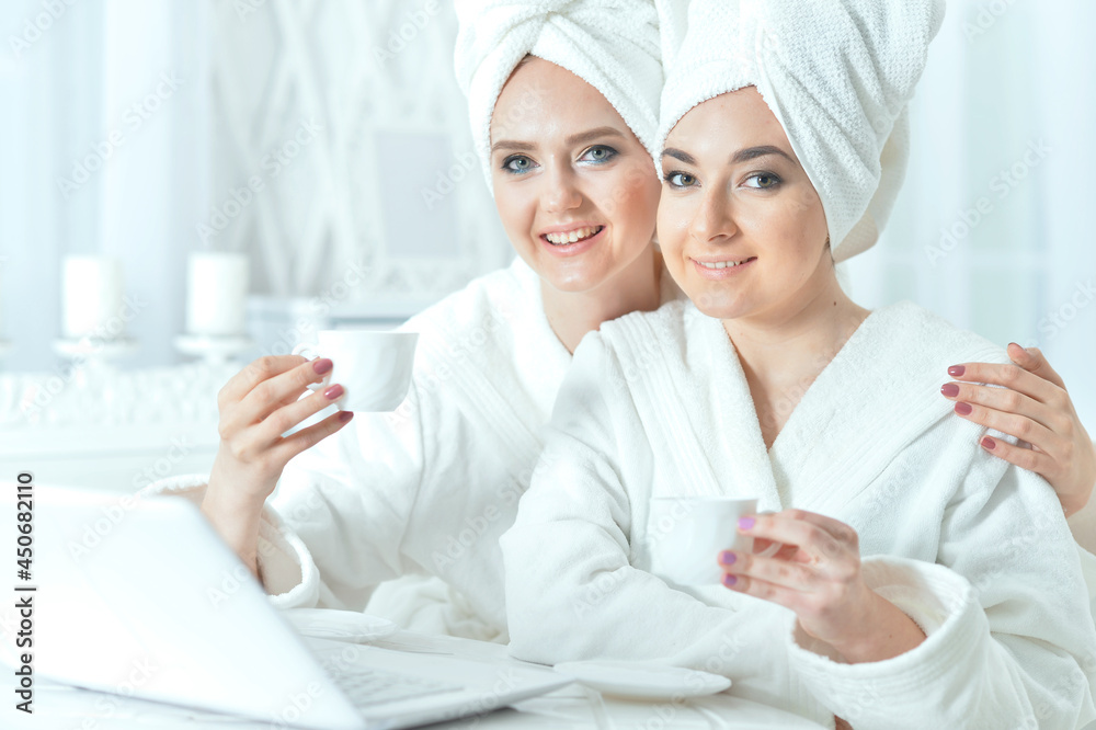 young women in bathrobes with laptop young women in bathrobes with laptop