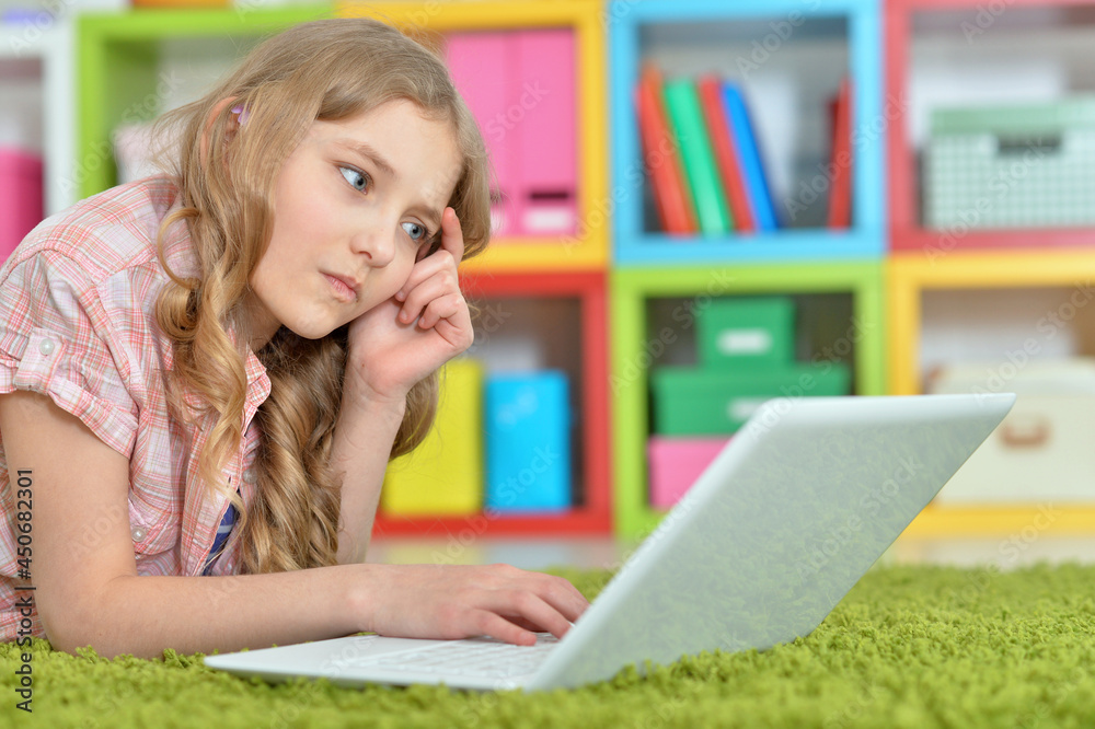 Cute girl using laptop while lying on green floor at home Cute girl using laptop while lying on green floor at home