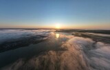 Flying over the clouds during morning sunrise in Carpathian Mountains. Above.Golden fluffy clouds moving softly on the sky and the sun shining through the clouds with beautiful rays and lens flare.