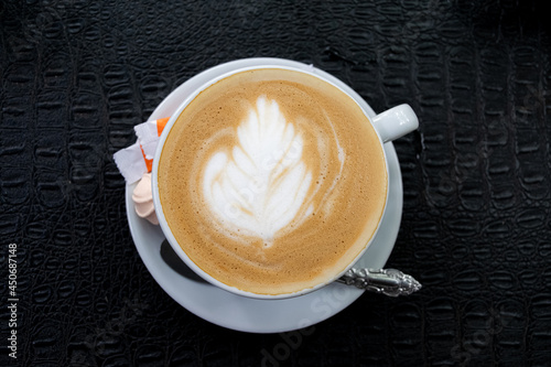 cappuccino with a flower pattern in a white cup on a black background