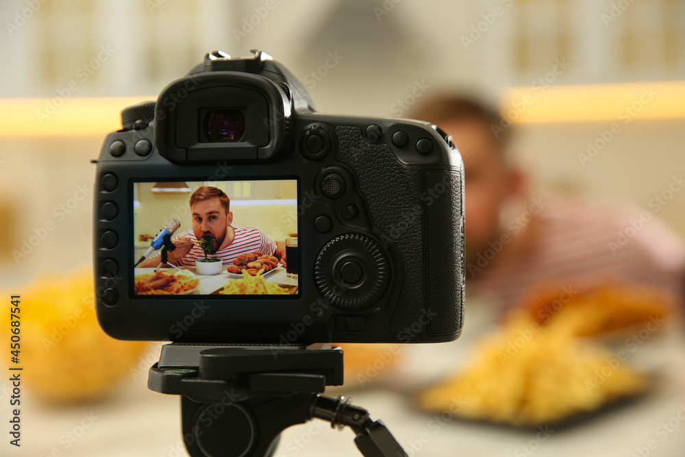 Food blogger recording eating show at table in kitchen, focus on camera screen. Mukbang vlog
