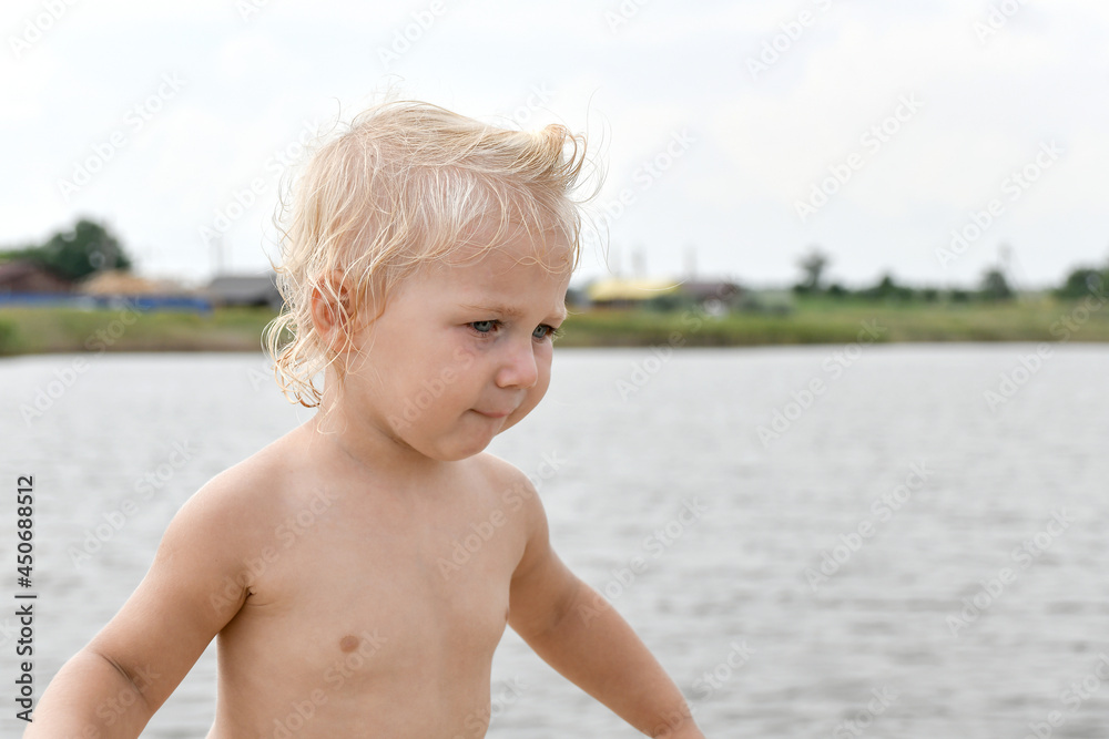 A child stands in bewilderment on the shore of a small lake. A child stands in bewilderment on the shore of a small lake.