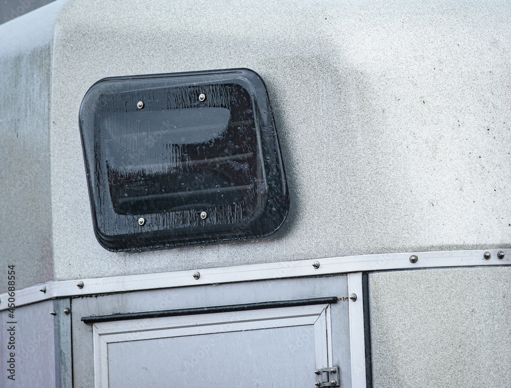 Window of a horse trailer under the rain